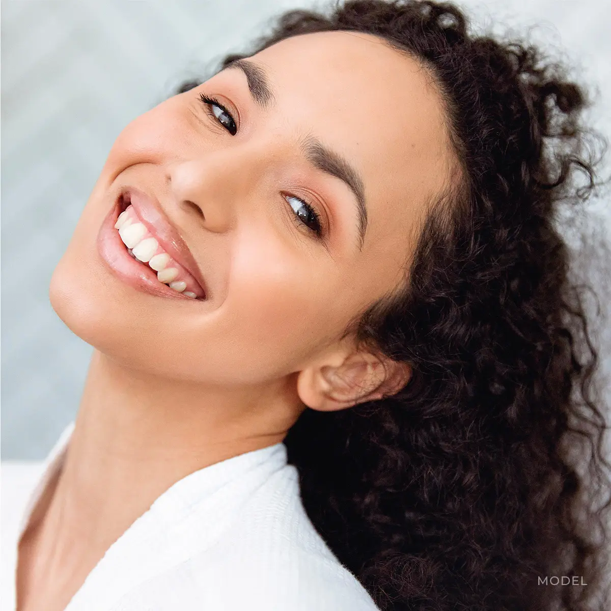 Woman with curly hair smiling, looking up