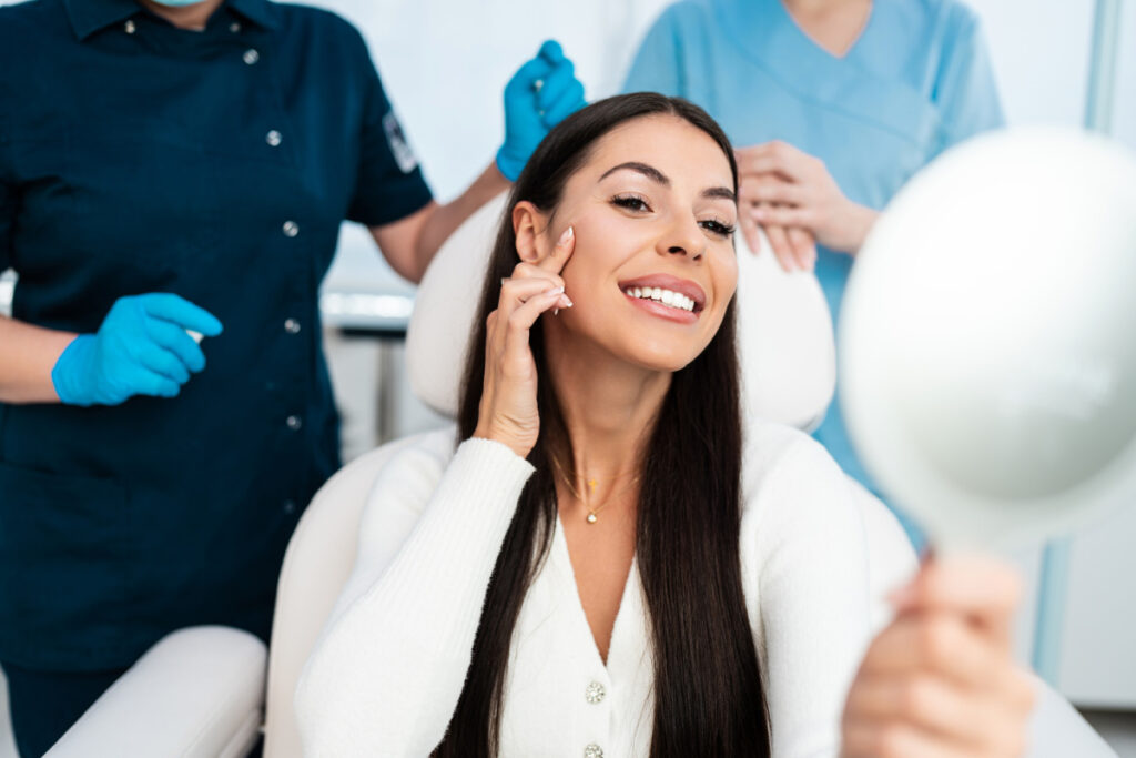 Woman smiling at results in the mirror after a med spa treatment